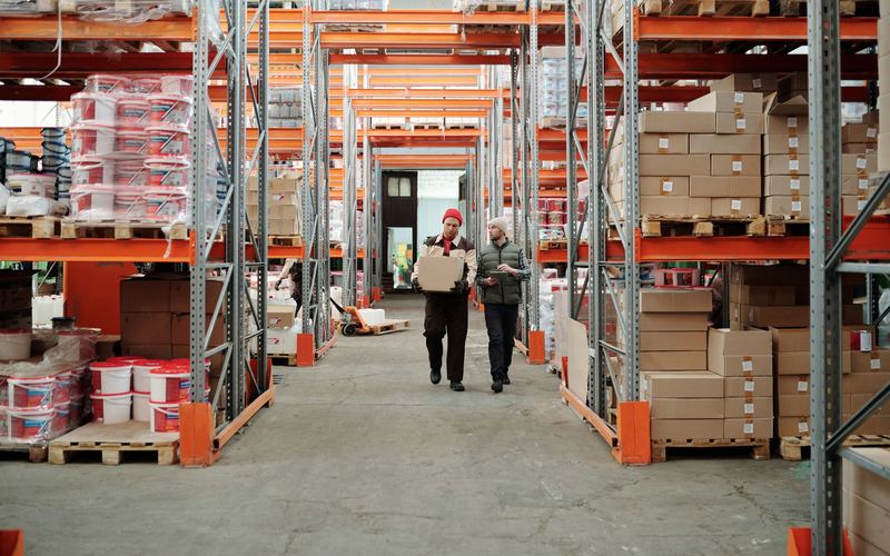 Workers walking a warehouse aisle lined with pallet racking